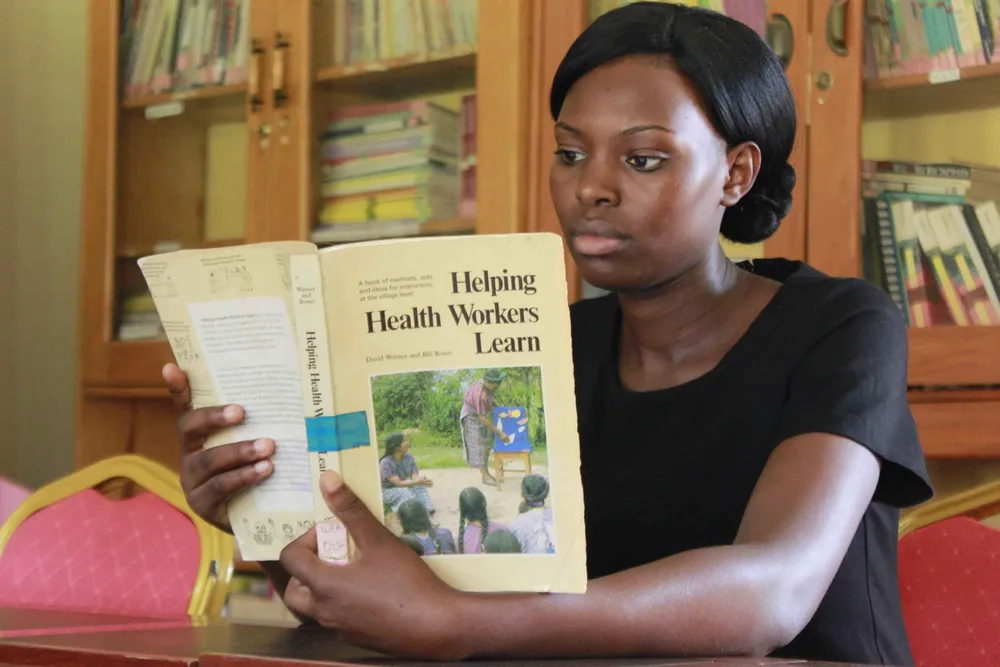 A reader exploring a health-worker training book in COMBRA’s resource centre